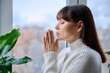 © Valerii Honcharuk - Middle aged woman folded hands in prayer meditation at home near window
