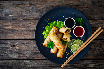 Poster - Spring rolls and sauces on wooden table
