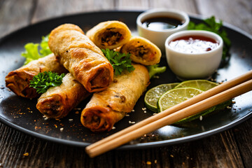 Wall Mural - Spring rolls and sauces on wooden table
