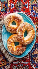 Poster - Three sesame seed bagels on a blue plate on a red rug. The bagels are arranged in a row and are ready to be eaten