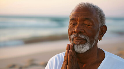 Wall Mural - Elderly man with eyes closed, meditating on a beach at sunset. Hands in prayer position, expressing tranquility and mindfulness.