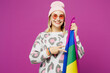 © ViDi Studio - Young happy smiling lesbian woman wear pink animal clothes hold in hands striped rainbow flag point on green color isolated on plain purple background studio. Pride day June month love LGBTQ concept.
