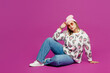 © ViDi Studio - Full body side view young smiling cool happy lesbian woman wear pink animal clothes sits looking camera isolated on plain purple background studio portrait. Pride day June month love LGBTQ concept.