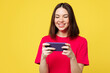 © ViDi Studio - Young gambling woman wear pink t-shirt casual clothes use play racing app on mobile cell phone hold gadget smartphone for pc video games isolated on plain yellow orange background. Lifestyle concept.