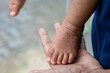 © Chamli_Pr - hand with hand-foot-mouth disease infected child's feet on an adult hand or HFMD originating from enterovirus or coxsackie virus, care for hand foot mouth disease
