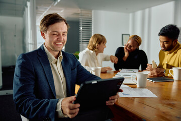 Wall Mural - Four young multiracial adults in businesswear working on digital tablet in meeting at office