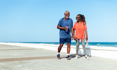 Wall Mural - Senior couple enjoying a sunny stroll on the seaside promenade