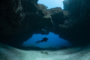 Wall Mural - woman diver visiting a cave under an arche