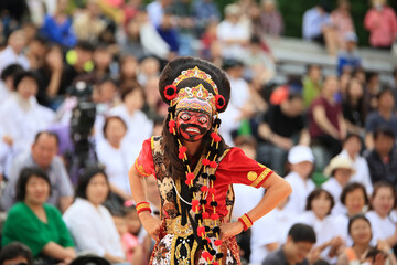 Wall Mural - A person performing a mask dance performance in a traditional Indonesian costume