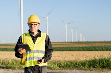 Poster - Engineer with digital tablet works on a field of wind turbines