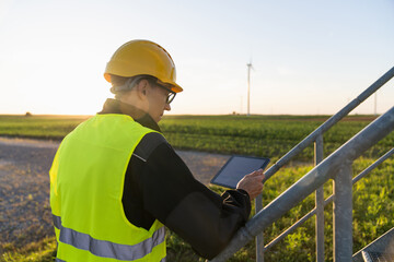 Poster - Engineer with digital tablet works on a field of wind turbines