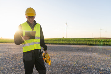 Poster - Engineer with digital tablet works on a field of wind turbines
