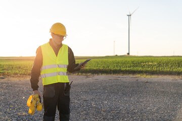 Poster - Engineer with digital tablet works on a field of wind turbines