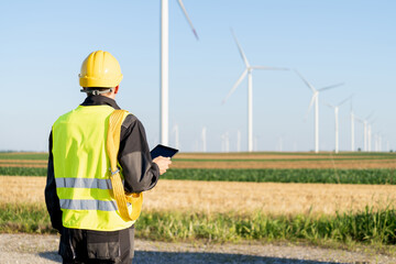 Poster - Engineer with digital tablet works on a field of wind turbines