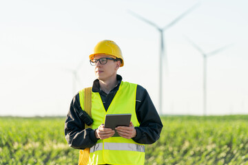Poster - Engineer with digital tablet works on a field of wind turbines