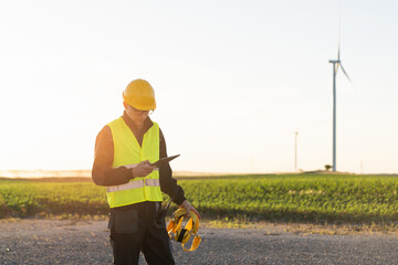 Poster - Engineer with digital tablet works on a field of wind turbines