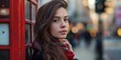 © Iryna - A pretty lady with red hair posing by a red telephone box in an urban street.
