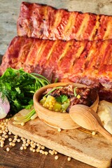 Wall Mural - Smoked meat ribs are lying on a wooden table. Soup with peas from ribs. There are raw peas and vegetables around. Meat production