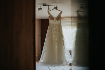 Wall Mural - A beautifully captured wedding dress hanging in a room, showcasing its intricate design and elegance against a serene backdrop