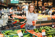 © Maria Vitkovska - Young woman choosing tomatoes while shopping for groceries at the supermarket