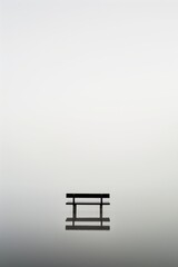 Fototapete - A bench is sitting in a lake with a foggy sky in the background. The bench is the only object in the scene, and it is empty