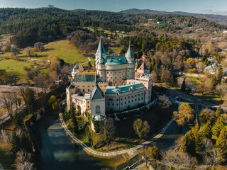 Aerial panoramic view of Bojnicky Zamok, medieval castle in Bojnice, Slovakia. Overhead scene of famous stone fortress and forest to horizon, landscape with historic buildings on hill with moat