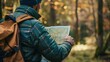 © Alice a. - A man with a beard is looking at a map while wearing a backpack. He is focused on the map and possibly planning a trip or navigating through the woods