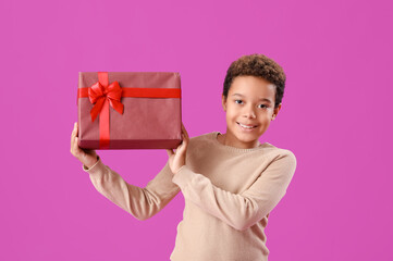 Poster - Little African-American boy with Christmas gift on purple background