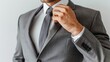 © Gefo - Elegantly dressed man adjusting tie in formal gray suit against white background
