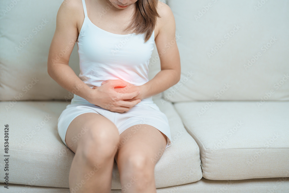 woman having abdomen ache due to Stomach pain, digestion with constipation or Diarrhea from food poisoning, female problem and Endometriosis, Hysterectomy, Stomachache and Menstrual on sofa at home