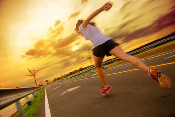 Wall Mural - Silhouette of young woman running sprinting on road. Fit runner fitness runner during outdoor workout with sunset background with high speed zoom blur effect.	