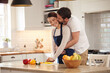 © peopleimages.com - Happy couple, cooking and embrace with kiss in kitchen at home for dinner, together as partners. Married people, affection and love or relationship for anniversary, celebration in house with bonding