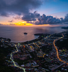 Aerial view Clouds obscure the beautiful sky as the sun sets. The lights along the beach begin to turn on as dusk approaches.There are many buildings, resorts, and hotels that accommodate tourists.