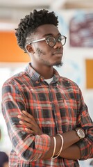 Wall Mural - Young Man in Plaid Shirt Standing With Arms Crossed in Modern Office