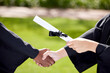 © peopleimages.com - University, handshake and hands of people at graduation with degree for success, achievement and education. College campus, school and students with certification, award and scroll for ceremony