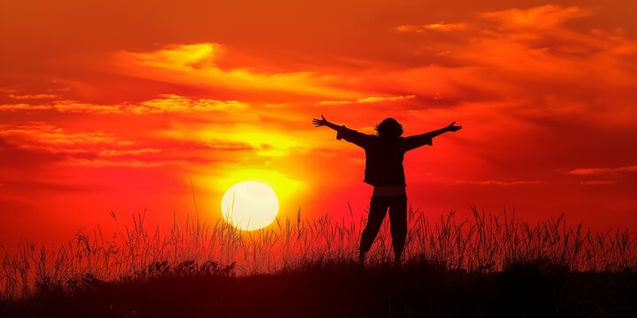 A joyful person with arms outstretched against a vivid sunset, depicting happiness and freedom