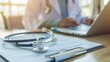© M - Stethoscope on prescription clipboard and Doctor working an Laptop on desk in hospital