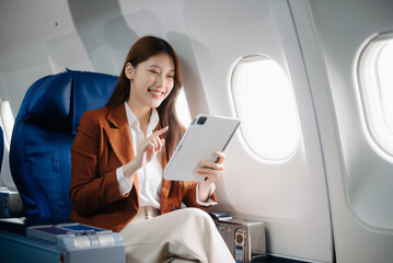 ￼Asian woman sitting in a seat in airplane and looking out the window going on a trip vacation travel concept.Capture the allure