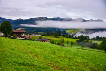 Wall Mural - Morning mist rising over Alpine valley in autumn colorful countryside
