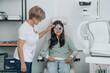 © Westend61 - Mature doctor examining girl wearing phoropter at eye clinic