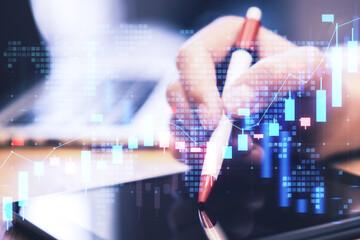 Wall Mural - Close up of male hand pointing at tablet with glowing blue candlestick forex chart on blurry background. Financial growth, stock and exchange concept. Double exposure.