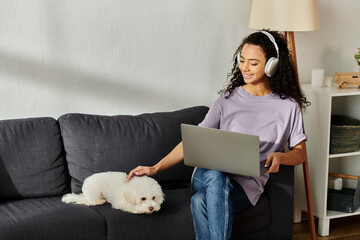 Wall Mural - Woman with laptop relaxes with her fluffy dog on a cozy couch.