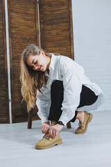 Wall Mural - A young woman ties shoelaces. Women's leather shoes.