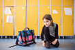 © Halfpoint - Portrait of schoolgirl, putting shoes on by lockers. Student girl with bag in hallway, after last day in elementary school before summer break.