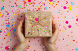 © Daniel - hands holding a present wrapped in craft paper with confetti