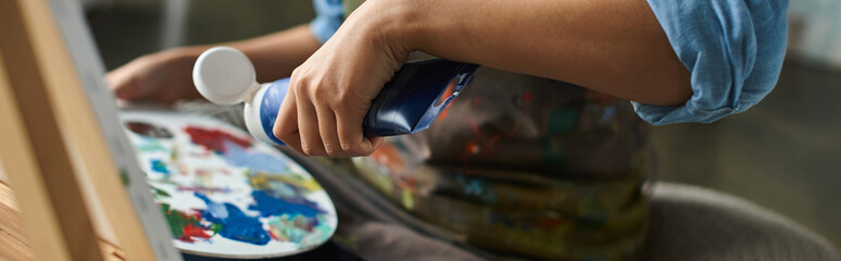 Wall Mural - Close-up of artists hand squeezing paint onto a palette.