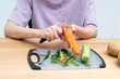 © Vitaliy - Close-up shot of a woman peeling vegetables using special vegetable peelers in the kitchen