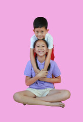 Wall Mural - Smiling Asian young girl child and little boy kid be happy while hugging each other isolated on pink background. Younger brother hugs older sister. Family relationship concept.