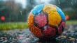 © svastix - Droplets of water bead on a multicolored soccer ball resting on a wet surface during rain