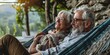© xartproduction - A couple of older people are sitting on a hammock, smiling at each other